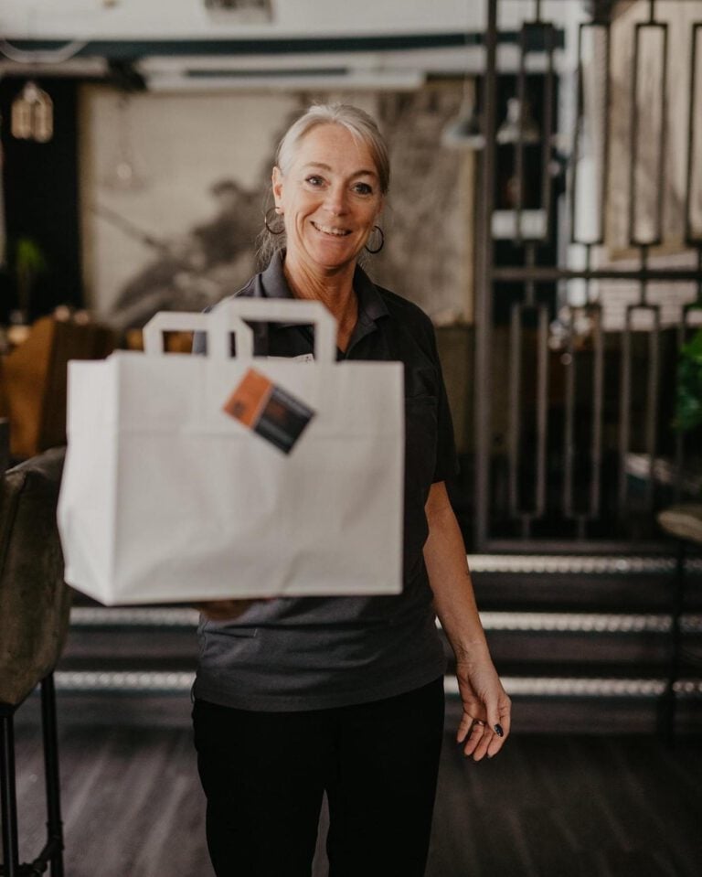 Simone van De Banjaard met een afhaalzak in haar handen in ons restaurant