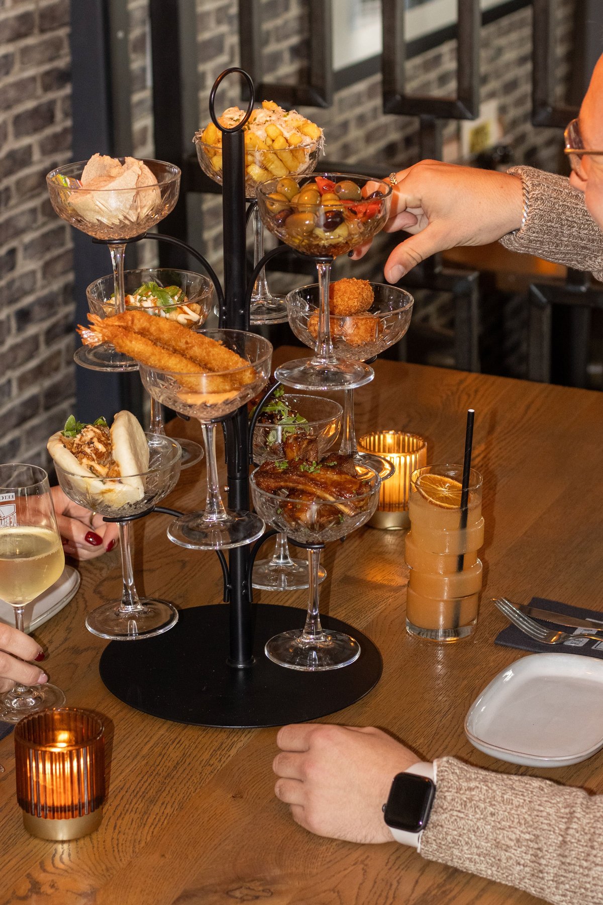 Etage met hapjes en snacks in kristallen glaasjes op een zwarte standaard op een gedekte tafel